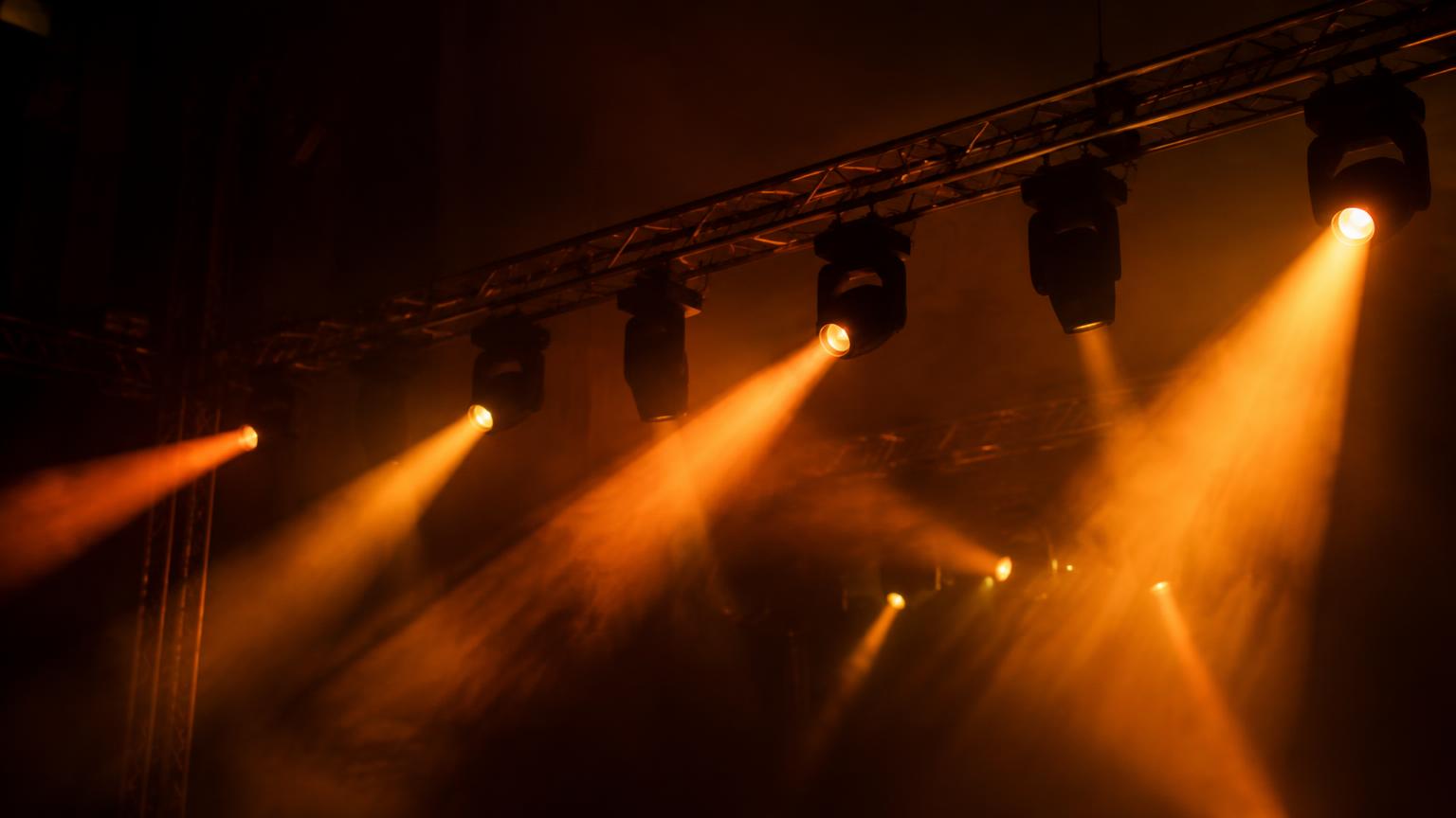 Scheinwerfer an einer Traverse, die warme Lichtstrahlen durch Nebel werfen